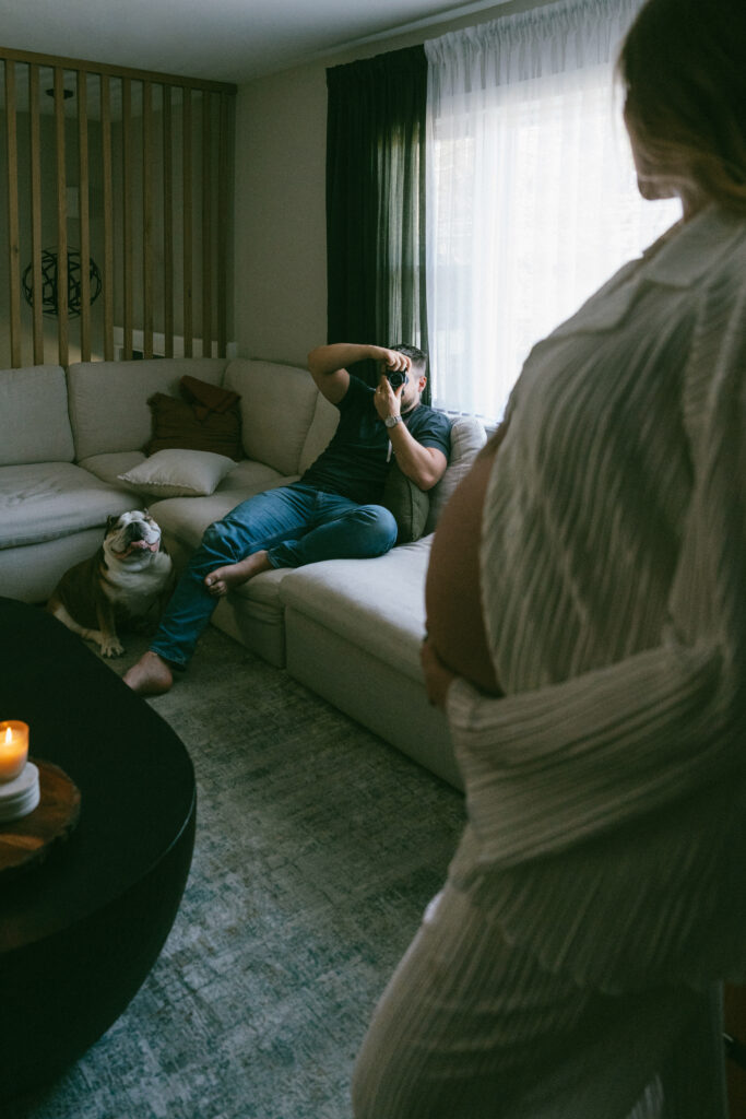 husband taking a posed photo of his wife holding her pregnant belly