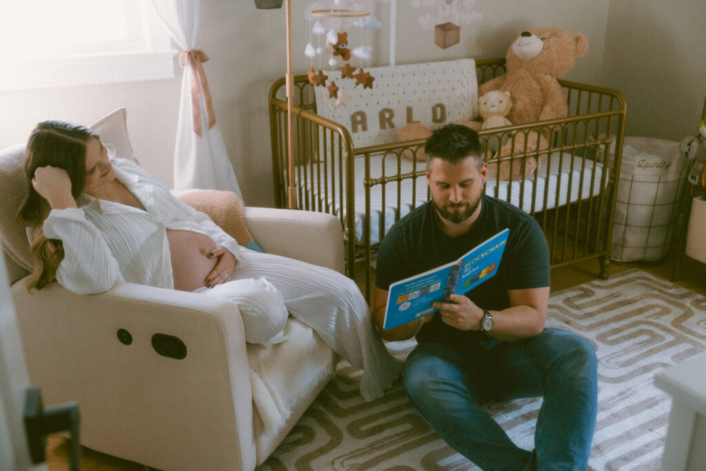 husband and wife reading a children's book in the nursery