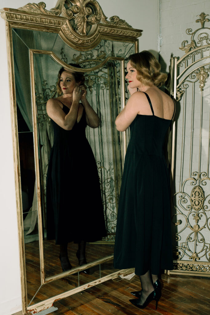 wife putting her earrings on in front of vintage mirror