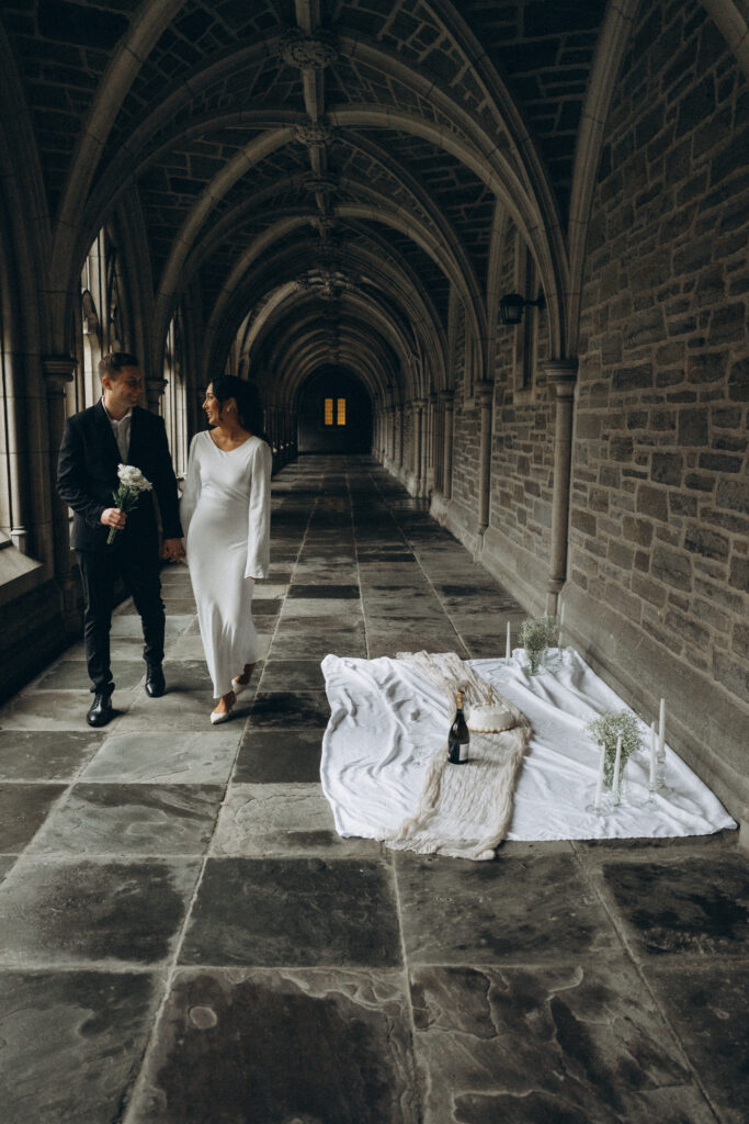 couple holding hands while walking with the husband holding a bouquet of white flowers