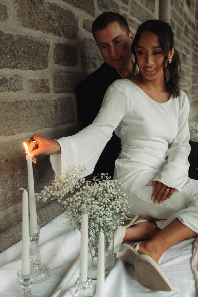 husband and wife cuddled close while she lights the candles