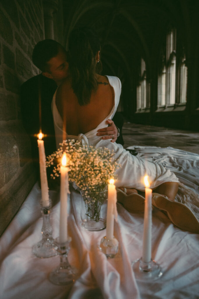 husband kissing wife of the neck while the candles glow behind them