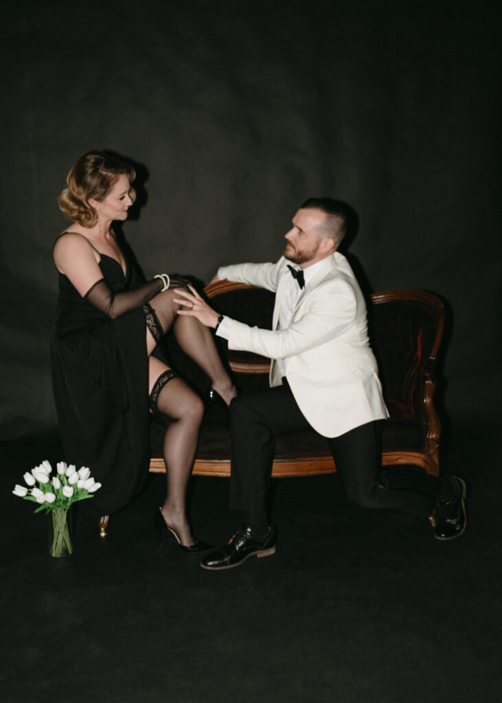 husband and wife sitting on couch while his hand rests on her leg