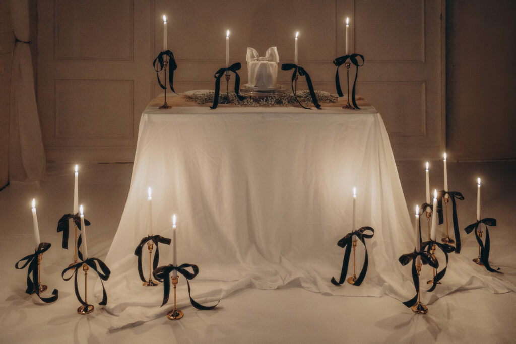 tablescape of lit candles with bows tied on them