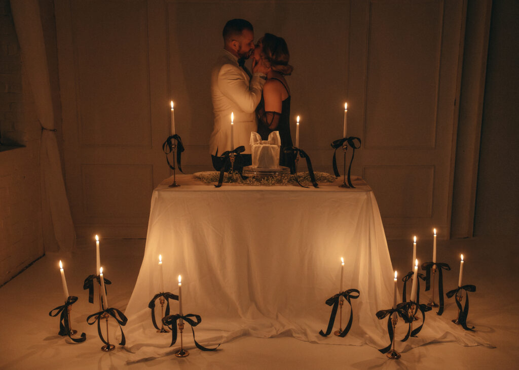 couple kissing behind candle lit table