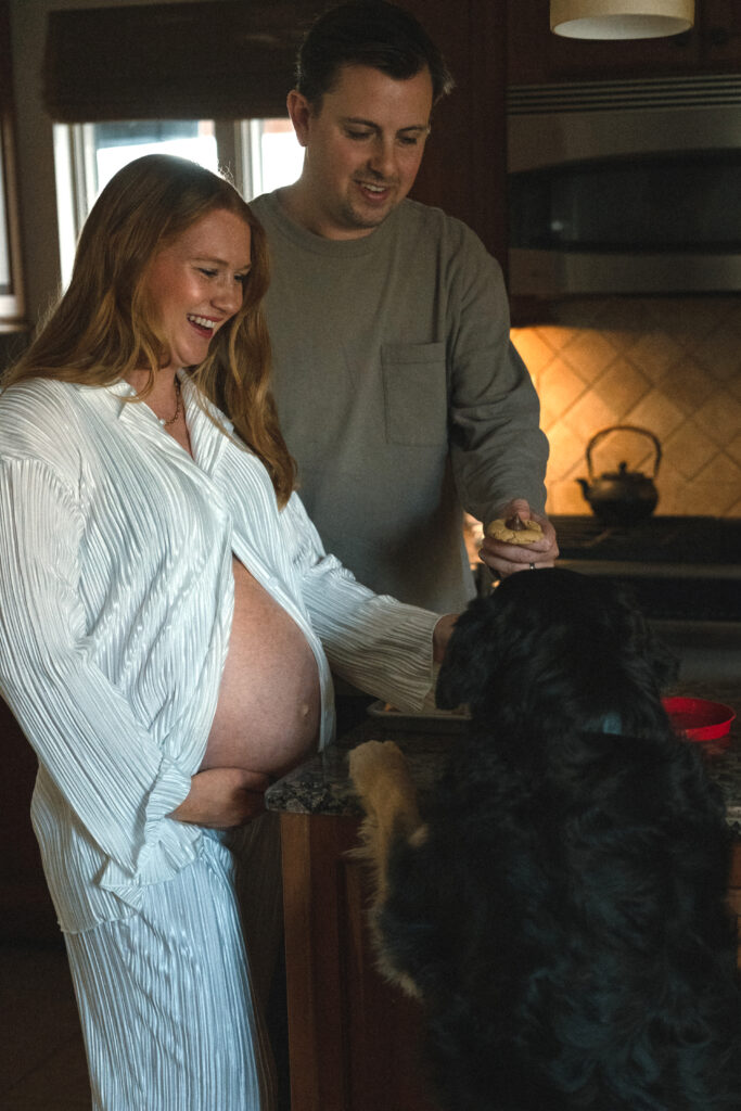 husband and wife making cookies while the dog is trying to jump up to get a bite