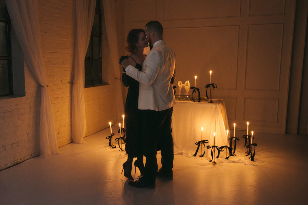 husband and wife slow dancing with candles lit in the background