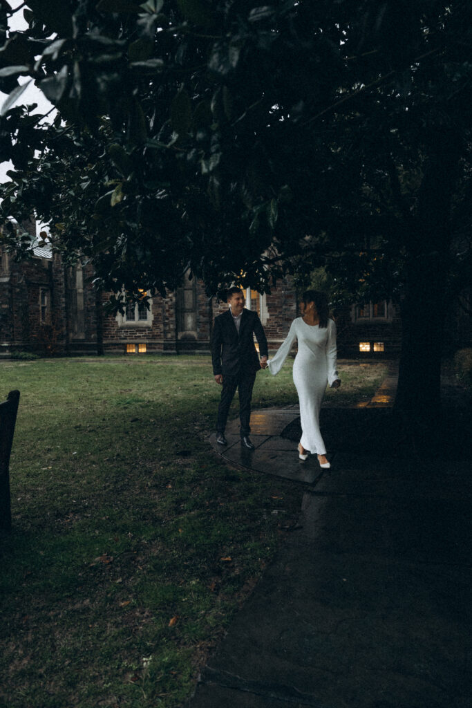 husband and wife walking together while wife guides her husband with her hand while looking behind at him