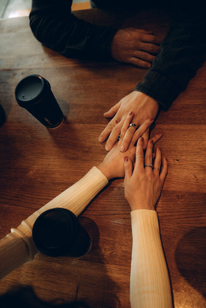 couple interlocking hands while enjoying coffee