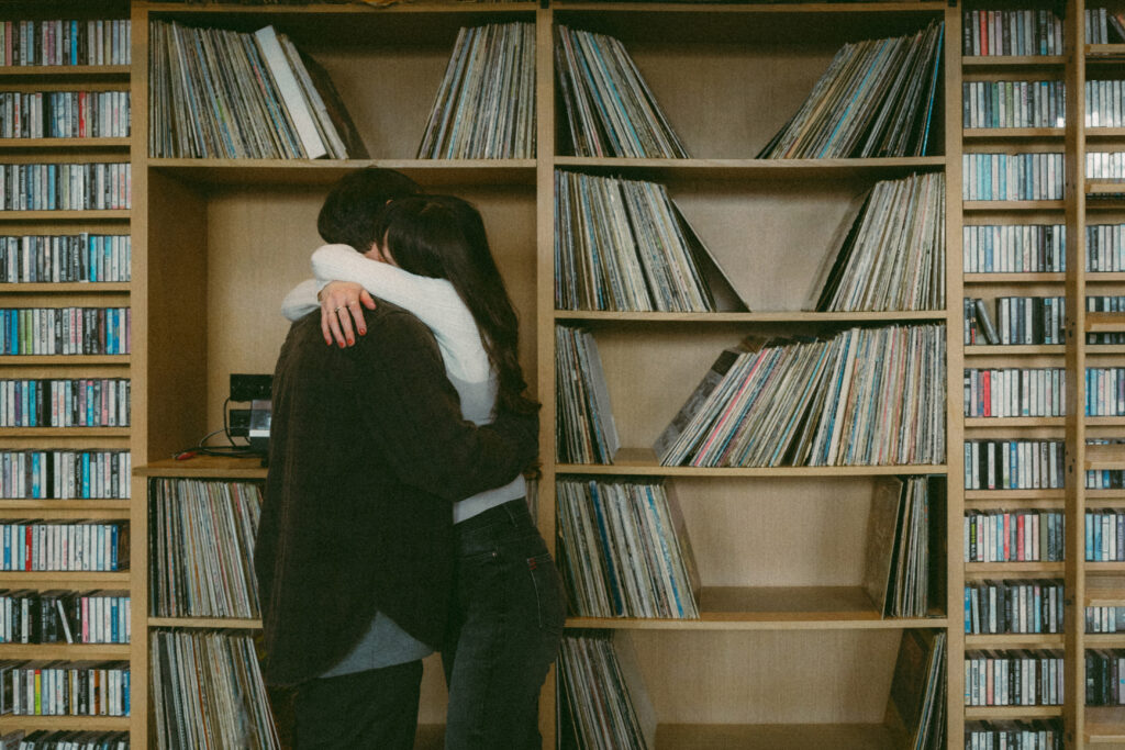 the couple sharing a hug with vintage vinyls in the background