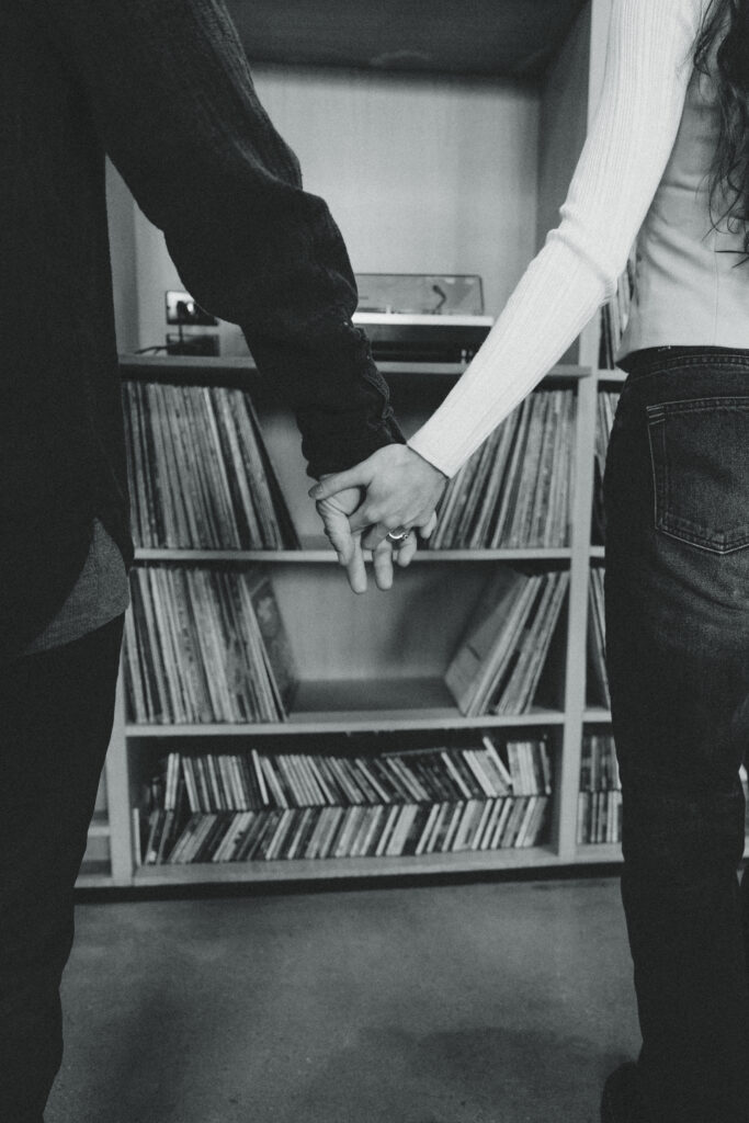 the couple holding hands with vintage vinyls in the background