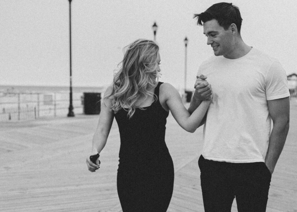 couple holding hands while walking on the boardwalk