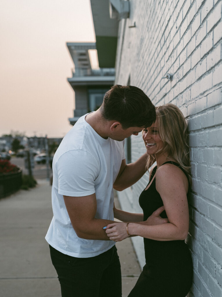 couple on the boardwalk where the woman is against a wall while her partner goes in for a kiss