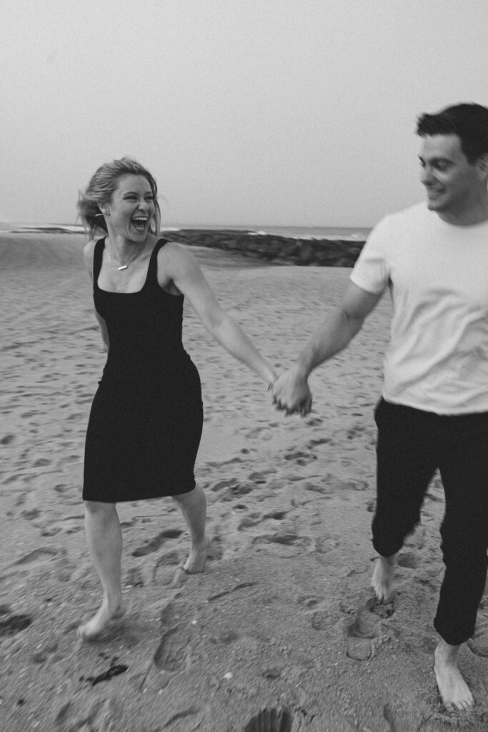 couple holding hands and laughing while running on the beach