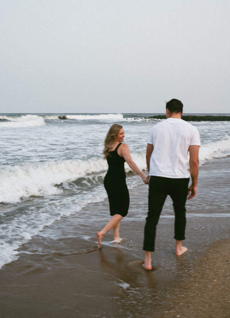 couple holding hands while walking by the water