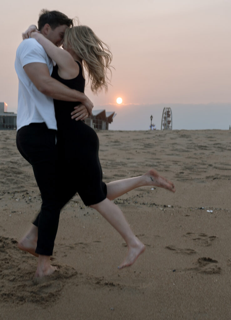 couple on beach while the man swings his partner around