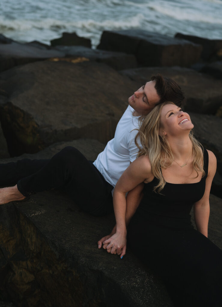 couple sitting and holding hands while sitting on rocks