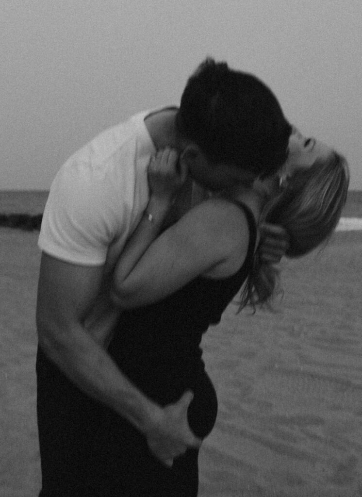 couple on beach where the man is kissing the woman on the neck while he grabs her butt