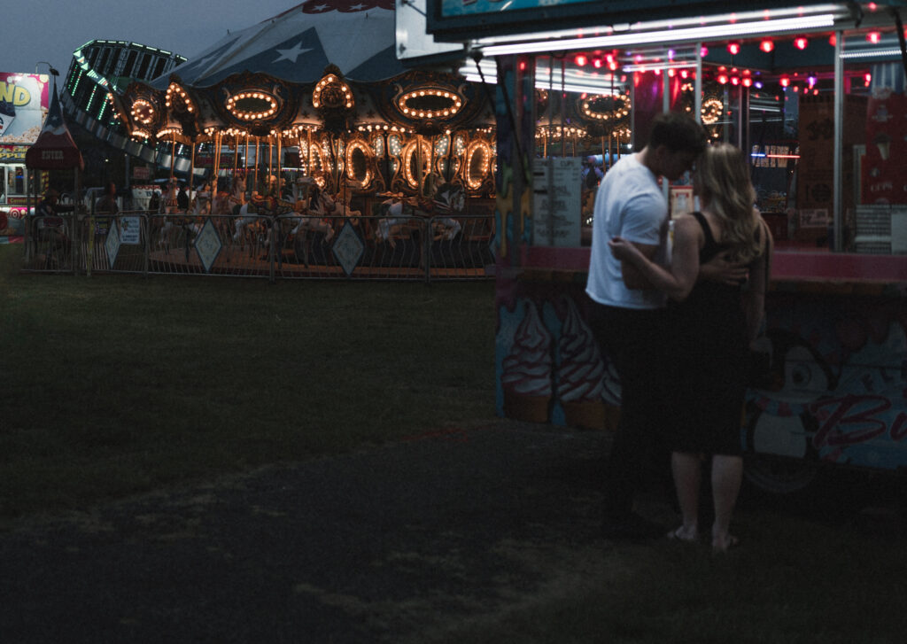 couple holding each other in front of ice cream stand