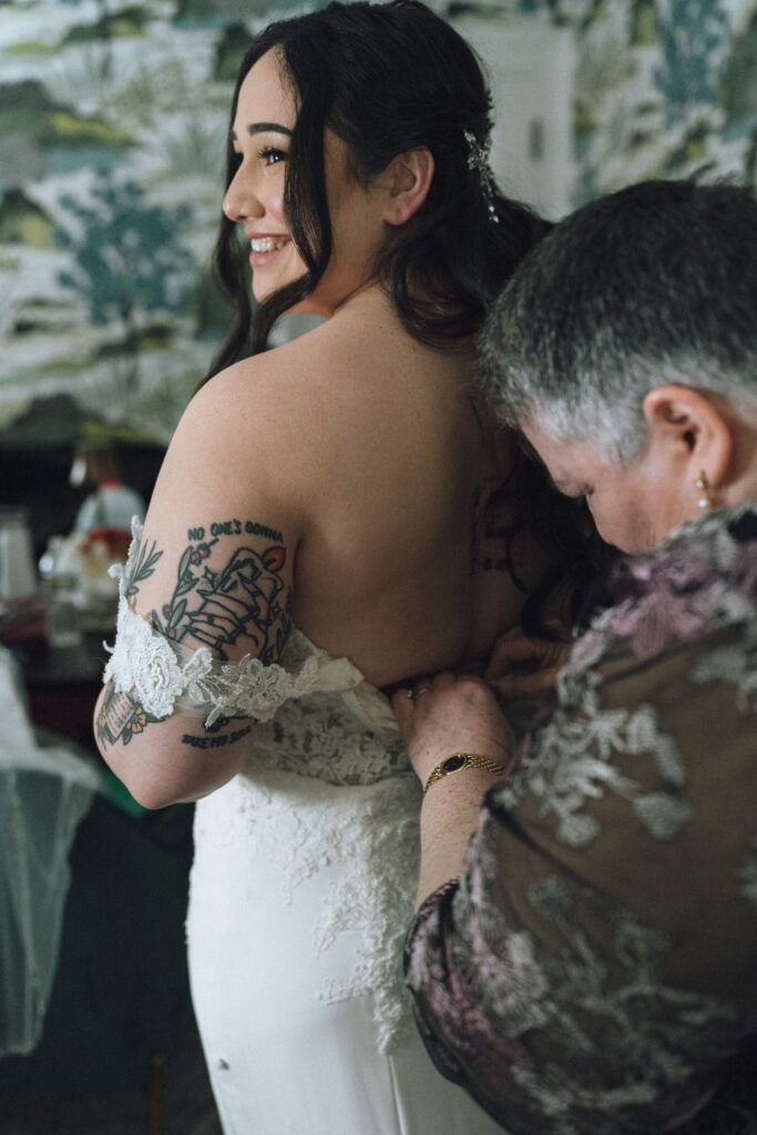 mother of the bride buttoning the bride's dress