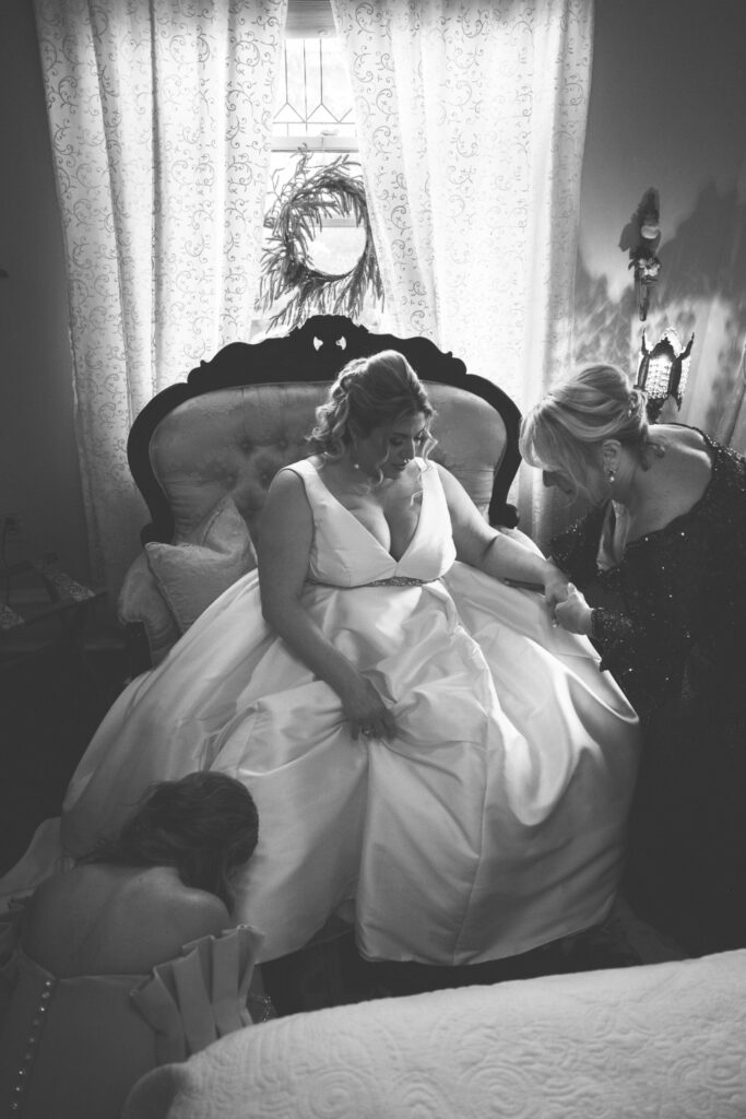 mother of the bride and bridesmaid helping her with her shoes