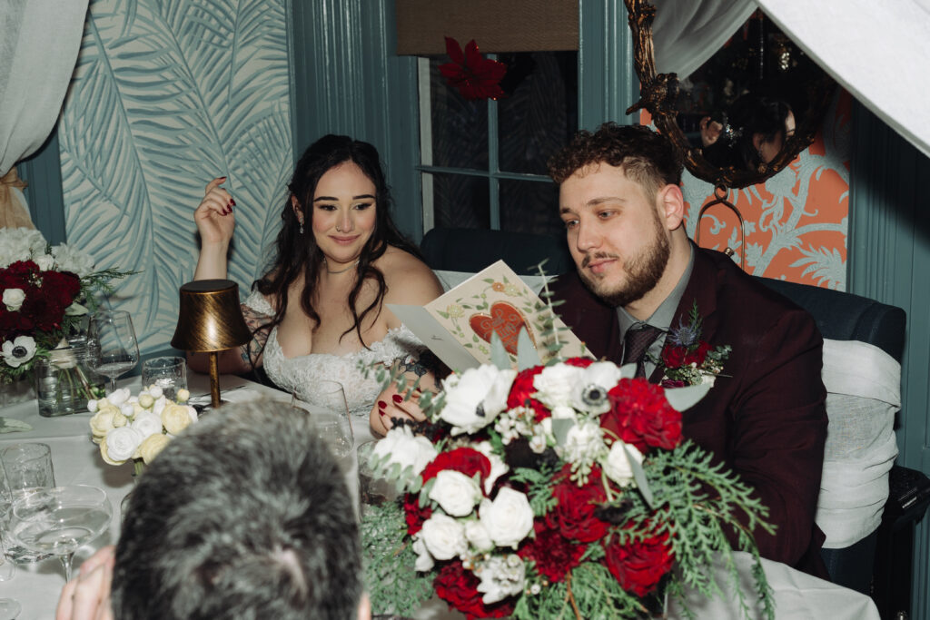 bride and groom at dinner reception table reading cards together