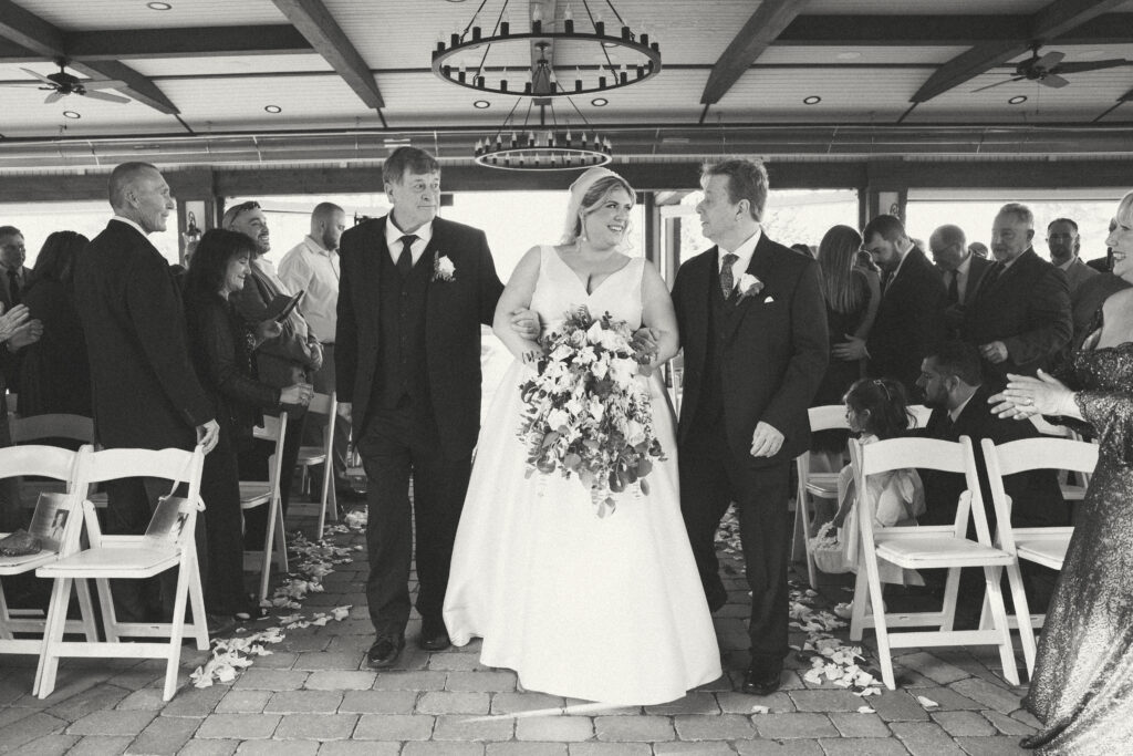 bride walking down the aisle with father and stepfather